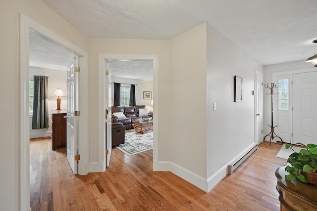 foyer with a baseboard heating unit, light wood-style flooring, and baseboards
