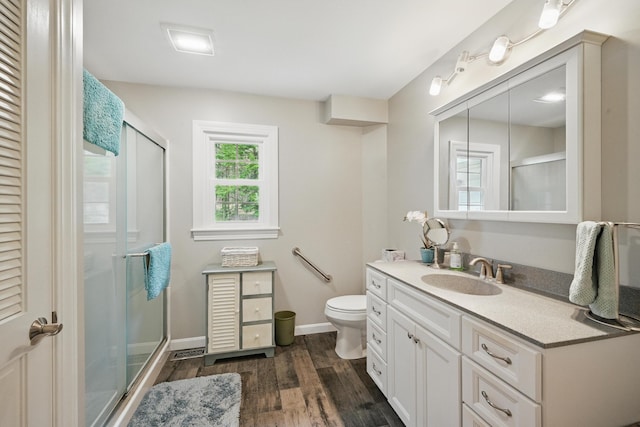 full bathroom featuring a shower stall, wood finished floors, vanity, toilet, and baseboards