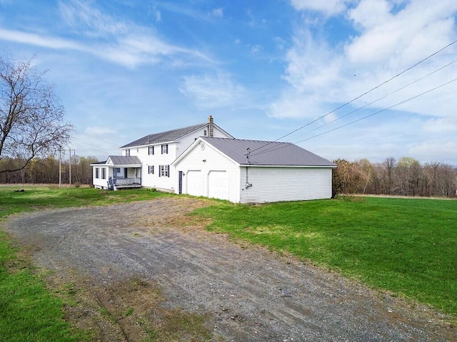 view of front of property featuring dirt driveway, a front yard, metal roof, and an attached garage