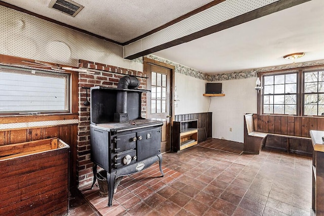 living room with a wood stove, a textured ceiling, and wallpapered walls