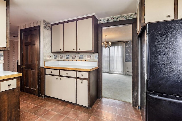 kitchen featuring freestanding refrigerator, wallpapered walls, light countertops, a chandelier, and baseboard heating