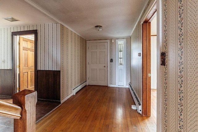corridor featuring wallpapered walls, baseboard heating, hardwood / wood-style flooring, and a textured ceiling