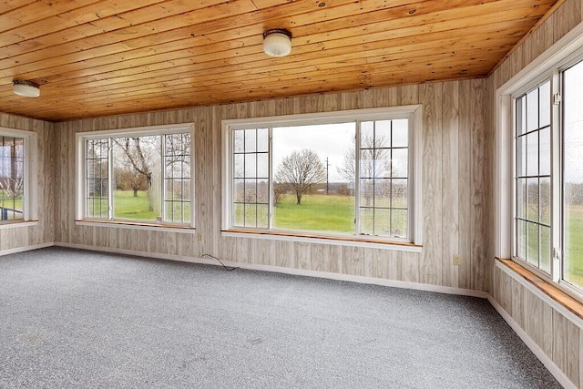 unfurnished sunroom with healthy amount of natural light, wood ceiling, carpet floors, and baseboards