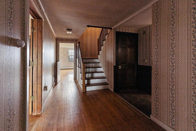 hallway with hardwood / wood-style flooring, a textured ceiling, stairs, and a baseboard heating unit