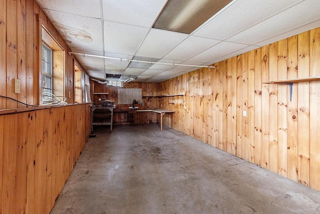 basement with wooden walls and a paneled ceiling