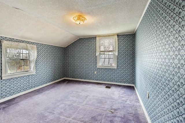 bonus room with vaulted ceiling, a textured ceiling, carpet flooring, baseboards, and wallpapered walls
