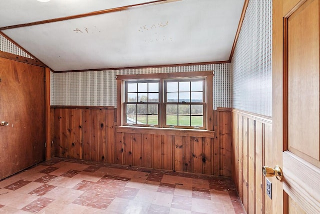 spare room with a wainscoted wall, tile patterned floors, wallpapered walls, wood walls, and lofted ceiling
