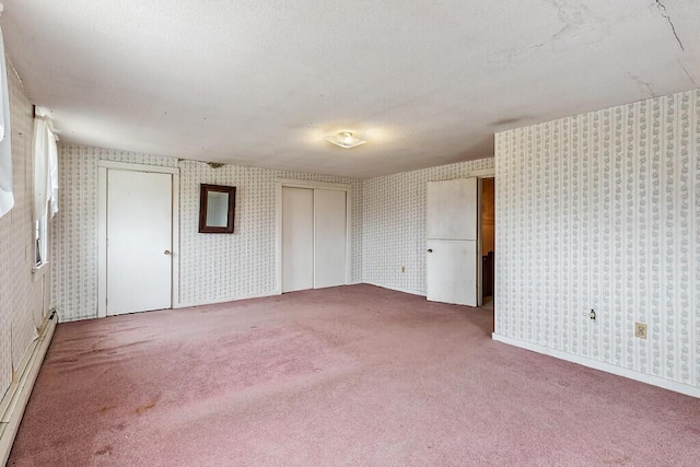 carpeted spare room featuring wallpapered walls and a baseboard radiator