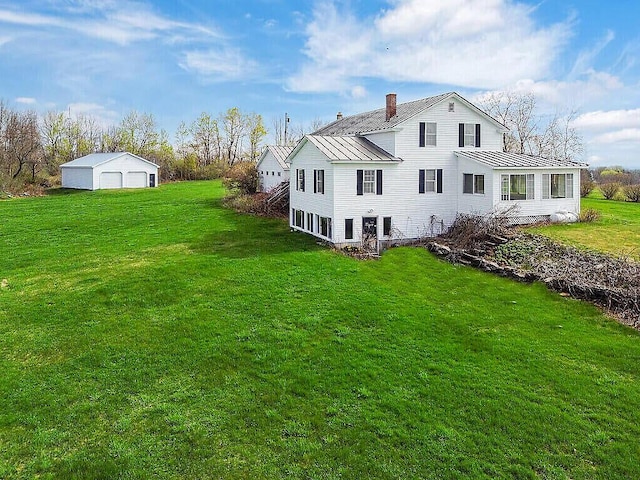 back of house with a chimney, metal roof, a standing seam roof, and a lawn