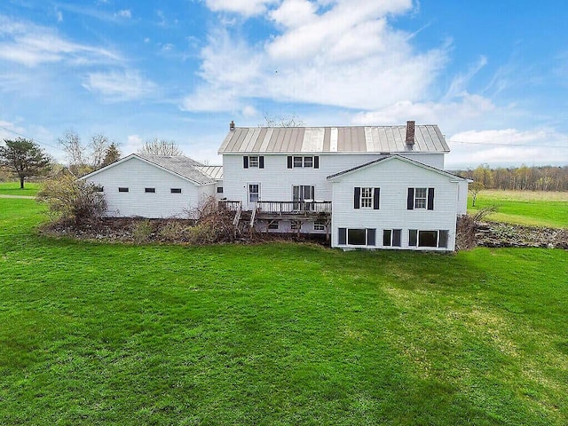 back of house with a yard, a wooden deck, and metal roof