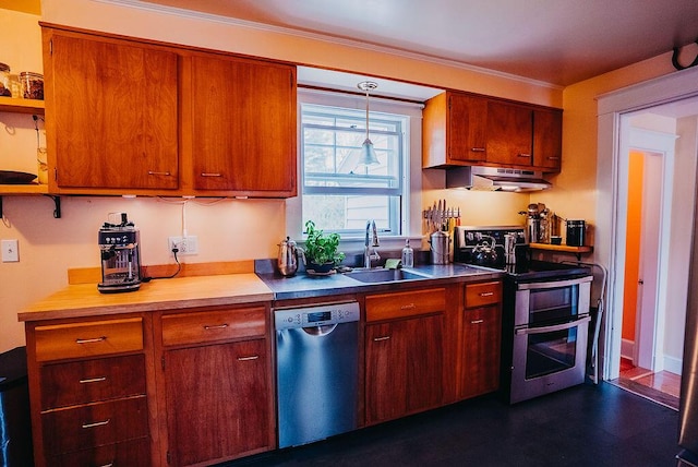 kitchen with appliances with stainless steel finishes, a sink, under cabinet range hood, brown cabinets, and decorative light fixtures