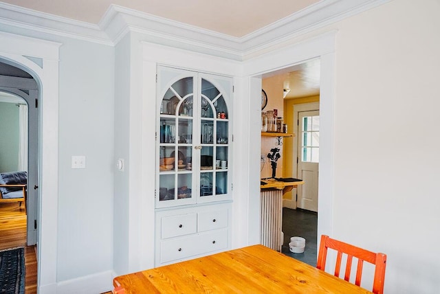 dining space featuring crown molding, baseboards, and arched walkways