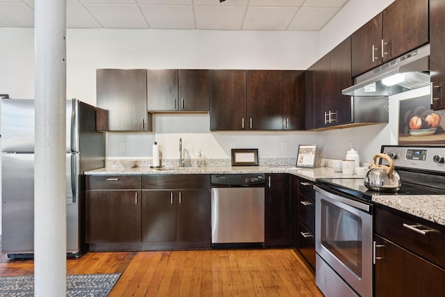 2 Main St Unit 17-410, Biddeford, ME 04005 - kitchen with appliances with stainless steel finishes, under cabinet range hood, a sink, decorative columns, and light wood-style floors