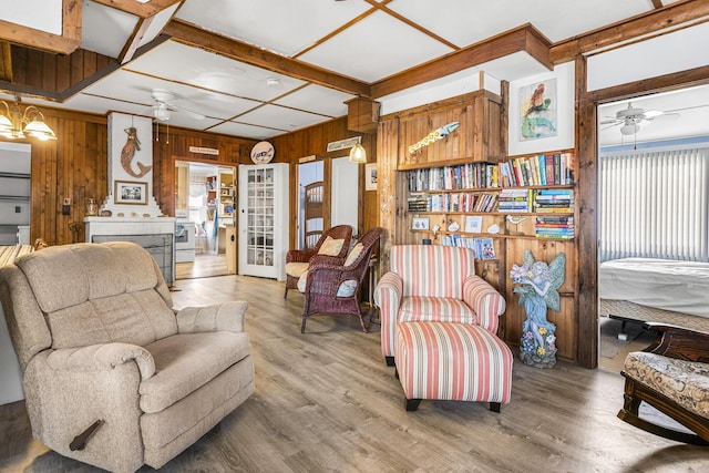 living area with a ceiling fan, wooden walls, light wood-type flooring, and french doors