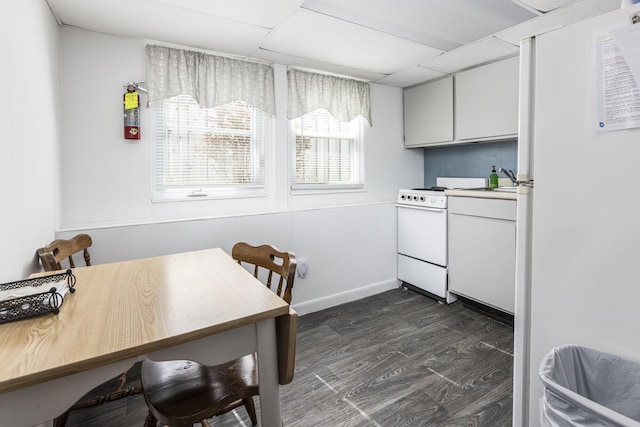 kitchen with white appliances, dark wood-type flooring, light countertops, and baseboards