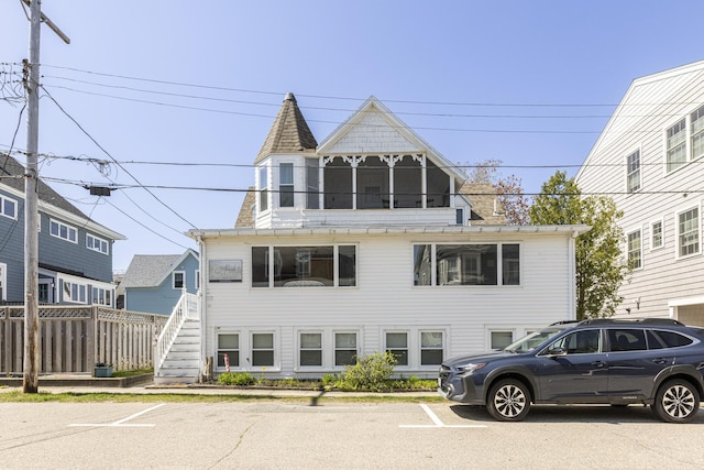 view of front of property featuring stairs, fence, a chimney, and uncovered parking