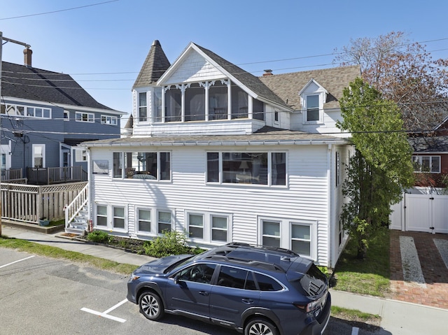 view of front of home featuring roof with shingles, fence, and uncovered parking