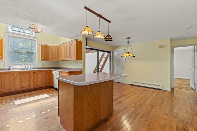 kitchen with a baseboard heating unit, a sink, a textured ceiling, light wood finished floors, and hanging light fixtures