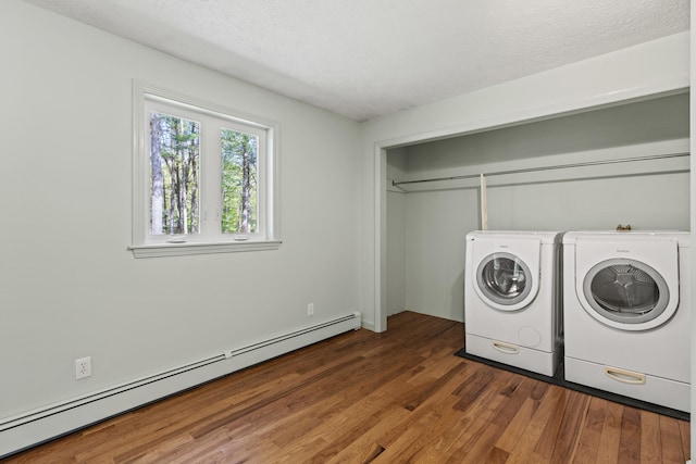 clothes washing area with baseboard heating, washing machine and dryer, wood finished floors, and a textured ceiling