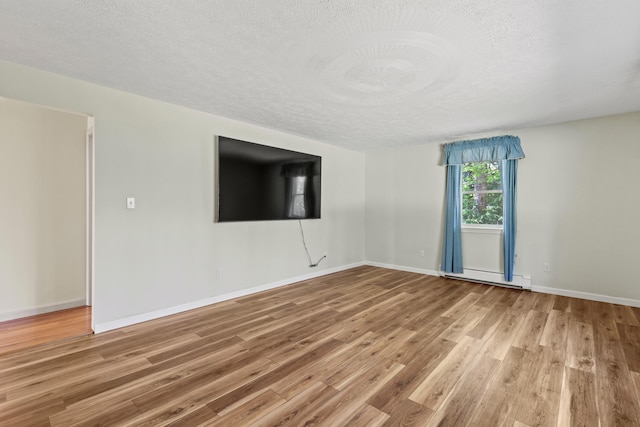 unfurnished room with wood finished floors, a textured ceiling, a baseboard radiator, and baseboards