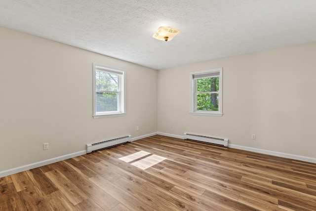 unfurnished room with a baseboard radiator, plenty of natural light, wood finished floors, and a textured ceiling