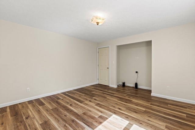 spare room with baseboards and wood finished floors