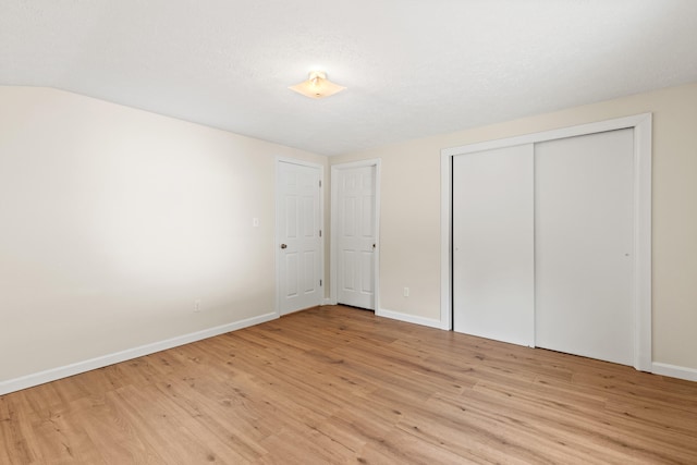unfurnished bedroom with light wood finished floors, baseboards, and a closet