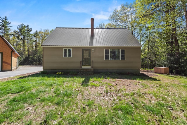 view of front of property featuring entry steps, metal roof, and a front yard