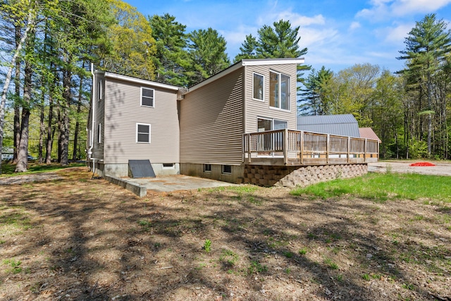back of house featuring a wooden deck and a patio