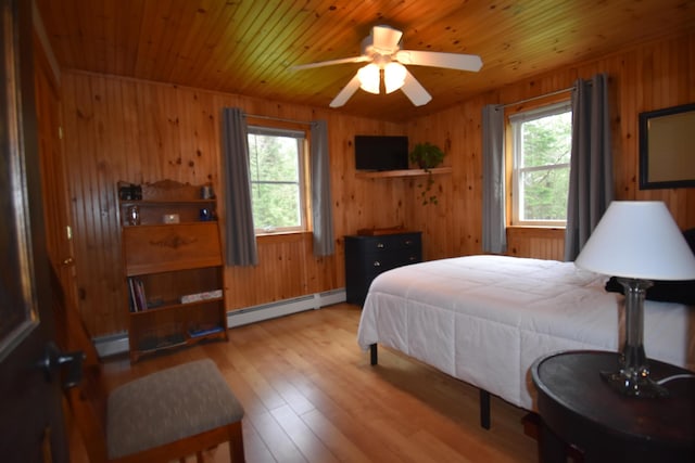 bedroom featuring a baseboard heating unit, multiple windows, wood-type flooring, wood walls, and wooden ceiling
