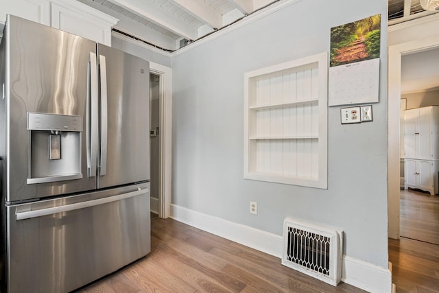 99 Spring St, Saco, ME 04072 - kitchen featuring stainless steel fridge with ice dispenser, baseboards, wood finished floors, beam ceiling, and white cabinetry