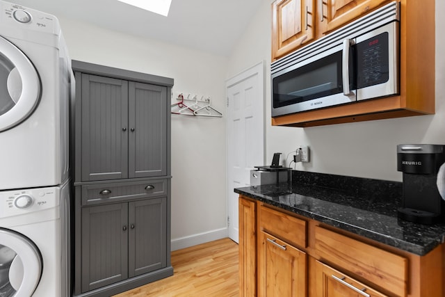 23 Amerescoggin Rd, Falmouth, ME 04105 - laundry area with estacked washer and dryer, light wood finished floors, baseboards, and a skylight