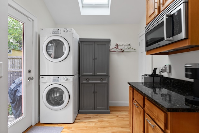 23 Amerescoggin Rd, Falmouth, ME 04105 - clothes washing area featuring stacked washer / drying machine, a skylight, light wood finished floors, and baseboards