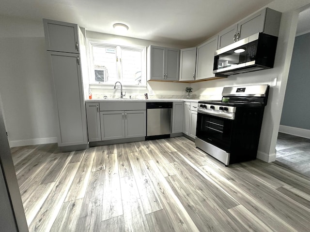 507 Waldo St, Rumford, ME 04276 - kitchen featuring stainless steel appliances, gray cabinets, a sink, baseboards, and light wood finished floors