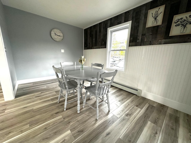 507 Waldo St, Rumford, ME 04276 - dining area featuring wood walls, a baseboard heating unit, baseboards, and wood finished floors