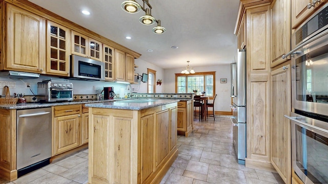 101 Parrott St, South Portland, ME 04106 - kitchen with appliances with stainless steel finishes, baseboards, a kitchen island, a sink, and glass insert cabinets