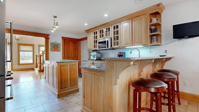 101 Parrott St, South Portland, ME 04106 - kitchen featuring stainless steel microwave, a peninsula, glass insert cabinets, a kitchen island, and a breakfast bar area