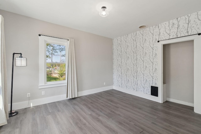 61 Granite St, Bath, ME 04530 - unfurnished living room with wood finished floors, baseboards, wallpapered walls, and an accent wall