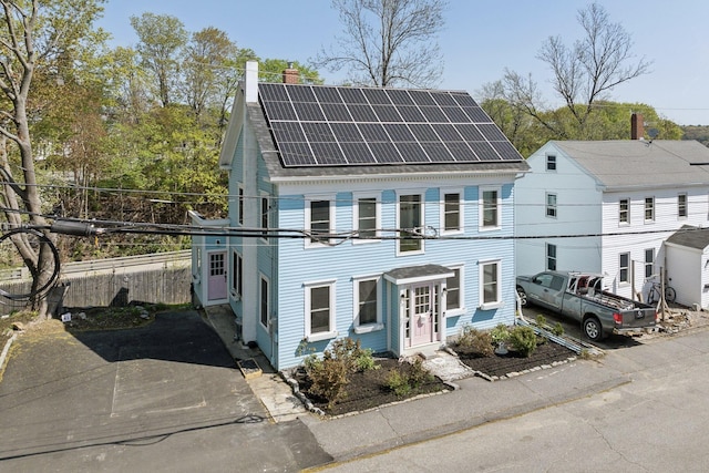 61 Granite St, Bath, ME 04530 - view of front of house featuring roof mounted solar panels, a chimney, and a shingled roof