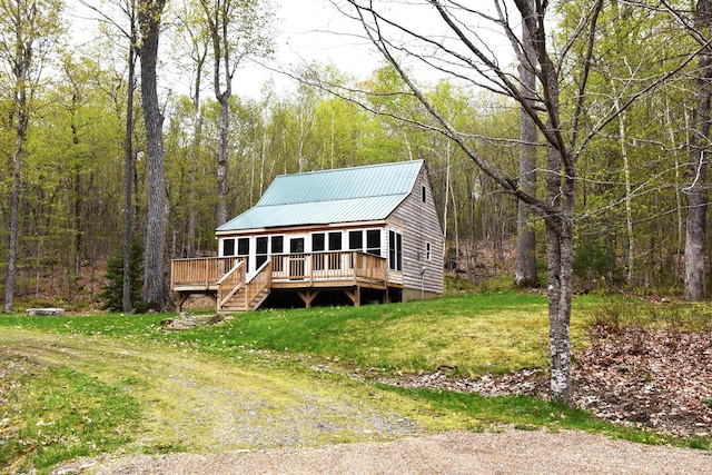 106 Shady Ln, Newport, ME 04953 - view of front of house with a forest view, a wooden deck, metal roof, and a front lawn