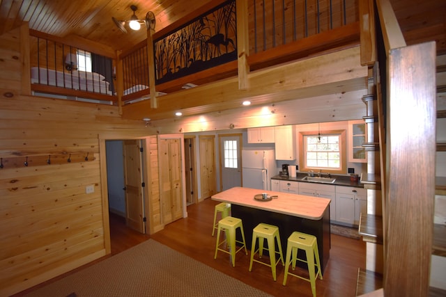 106 Shady Ln, Newport, ME 04953 - kitchen with freestanding refrigerator, a sink, wooden walls, white cabinets, and a breakfast bar