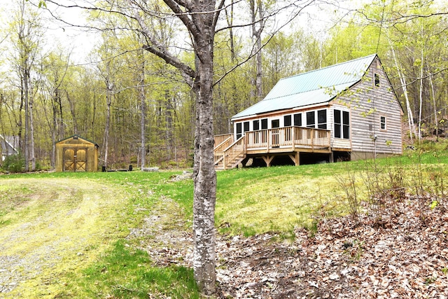 106 Shady Ln, Newport, ME 04953 - rear view of property featuring a wooden deck, a storage shed, a wooded view, an outdoor structure, and metal roof