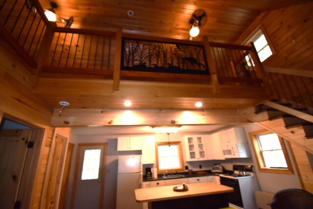 106 Shady Ln, Newport, ME 04953 - kitchen featuring white appliances, white cabinetry, a center island, plenty of natural light, and wood walls