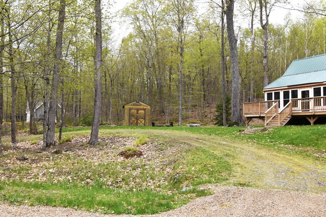 106 Shady Ln, Newport, ME 04953 - view of yard featuring a storage unit, a wooden deck, an outdoor structure, and a forest view