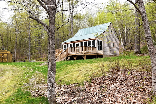 106 Shady Ln, Newport, ME 04953 - rear view of house featuring a deck, a storage unit, a wooded view, metal roof, and an outbuilding
