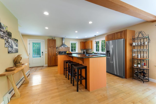 400 Chopps Cross Rd, Woolwich, ME 04579 - kitchen featuring stainless steel refrigerator with ice dispenser, wall chimney range hood, a breakfast bar, a center island, and brown cabinetry