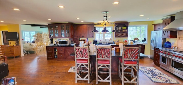 281 Cross Rd, Washburn, ME 04786 - kitchen featuring appliances with stainless steel finishes, wall chimney exhaust hood, recessed lighting, dark wood-style flooring, and a breakfast bar area