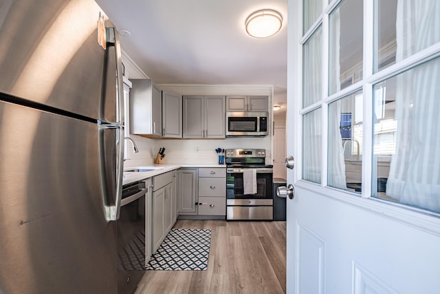 301 Sherwood St, Portland, ME 04103 - kitchen featuring stainless steel appliances, gray cabinets, a sink, light wood finished floors, and light countertops