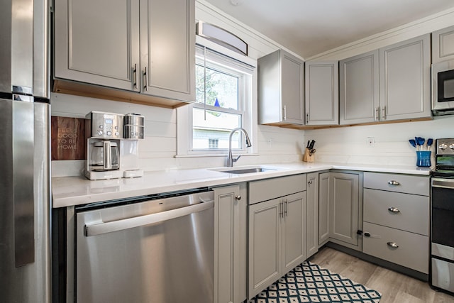 301 Sherwood St, Portland, ME 04103 - kitchen featuring gray cabinetry, stainless steel appliances, a sink, and light wood-style floors