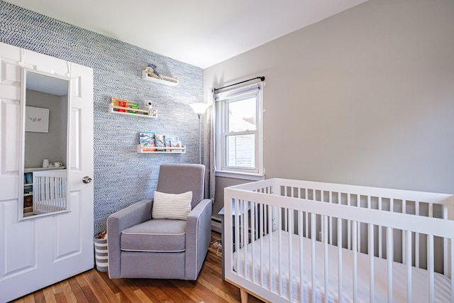 301 Sherwood St, Portland, ME 04103 - bedroom with a nursery area, wood finished floors, and a baseboard heating unit